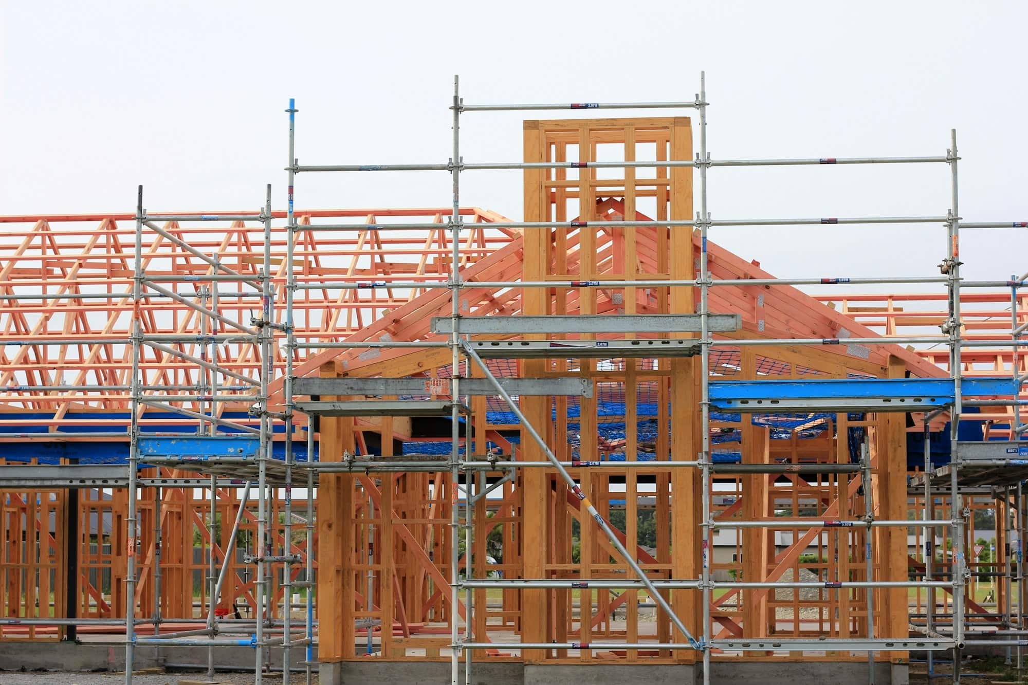 A new home under construction, timber frame and scaffolding against the sky.