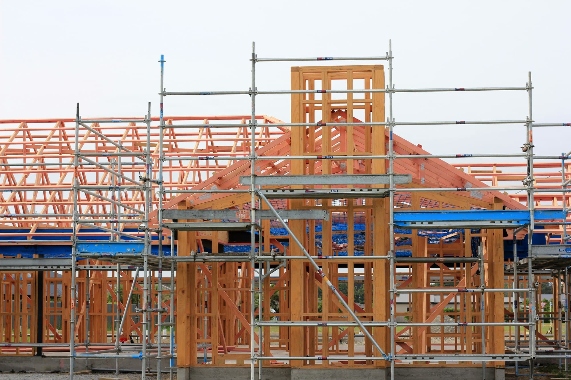 A new home under construction, timber frame and scaffolding against the sky.